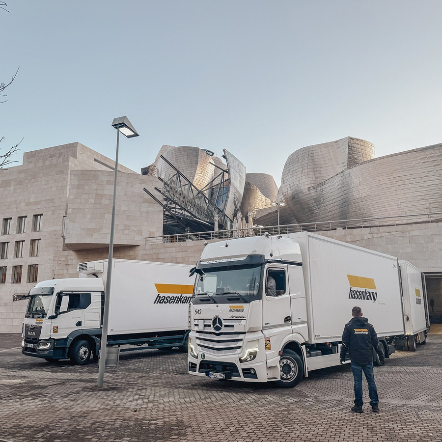 Zwei parkende LKWs vor einem garuen Museumsgebäude