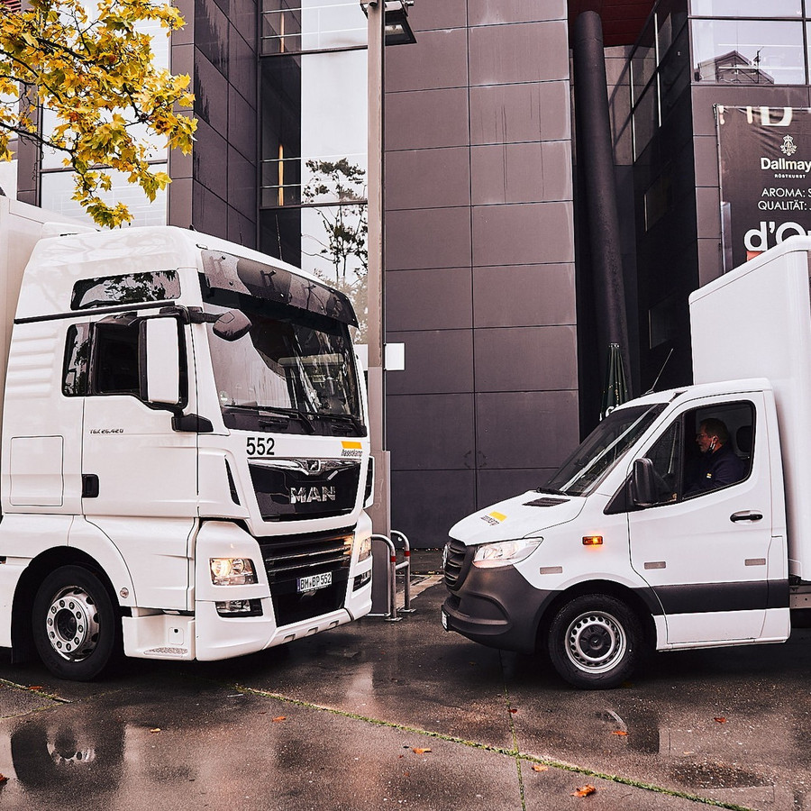 Großer LKW und Transporter stehen sich gegenüber vor einem Gebäude